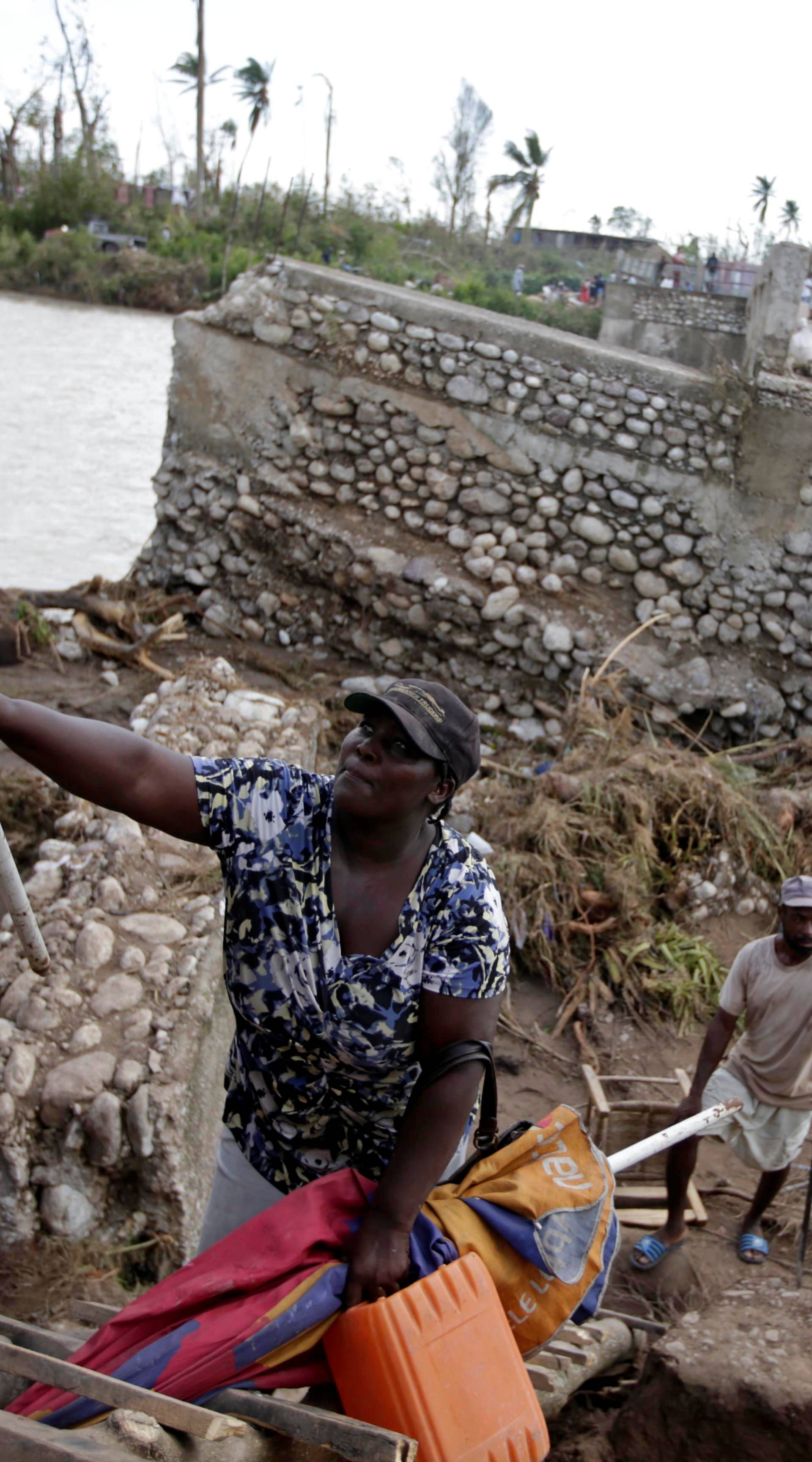 People use a handmade ladder after the bridge has been destroyed by Hurricane Matthew in Chantal