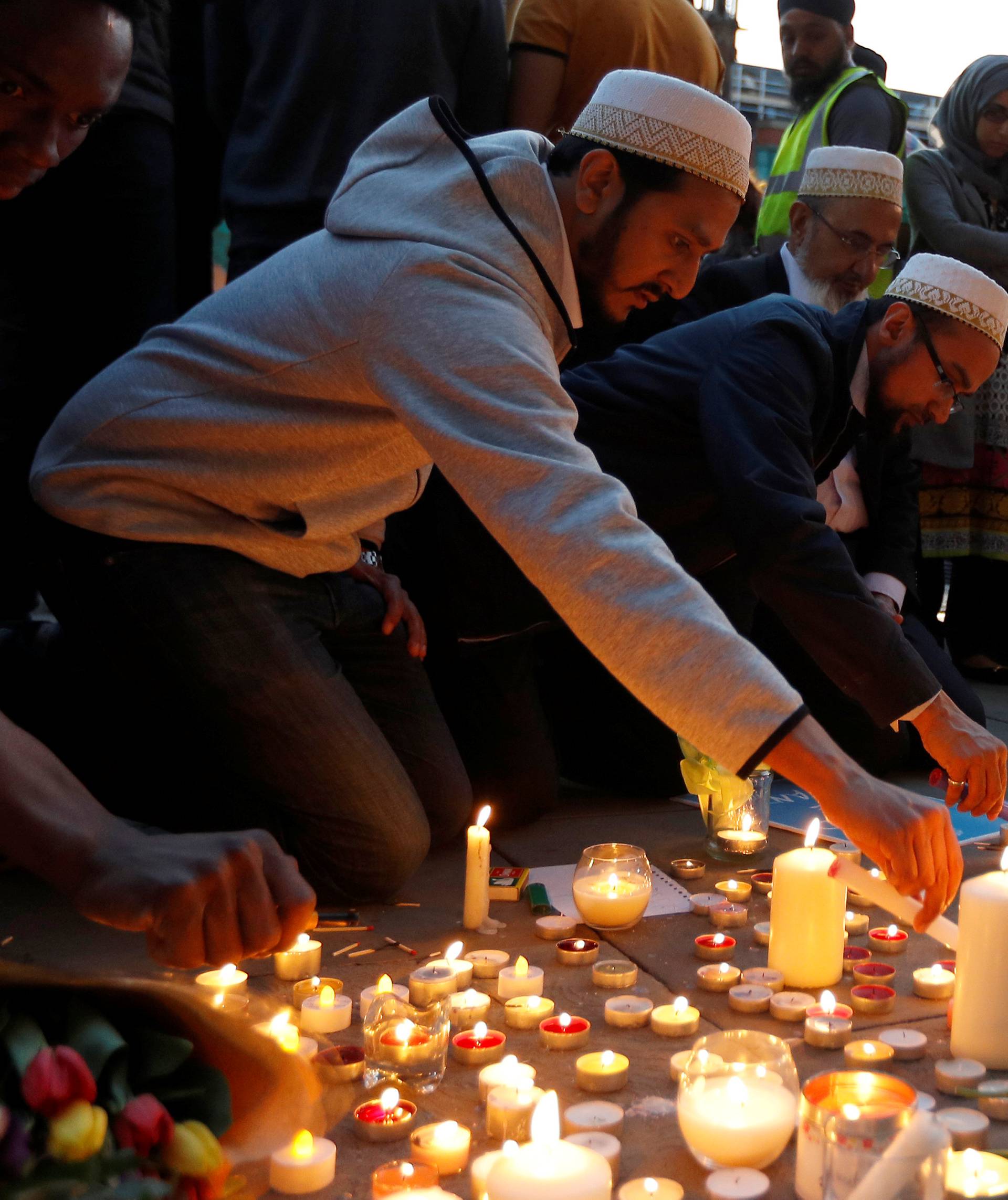 Men light candles following a vigil in central Manchester
