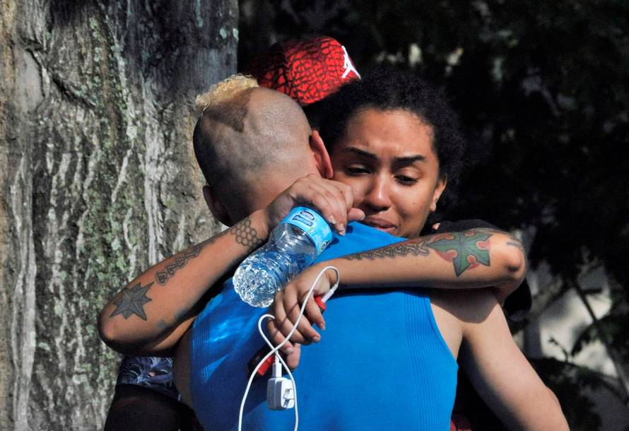 Friends and family members embrace outside the Orlando Police Headquarters during the investigation of a shooting at the Pulse nightclub in Orlando, Florida