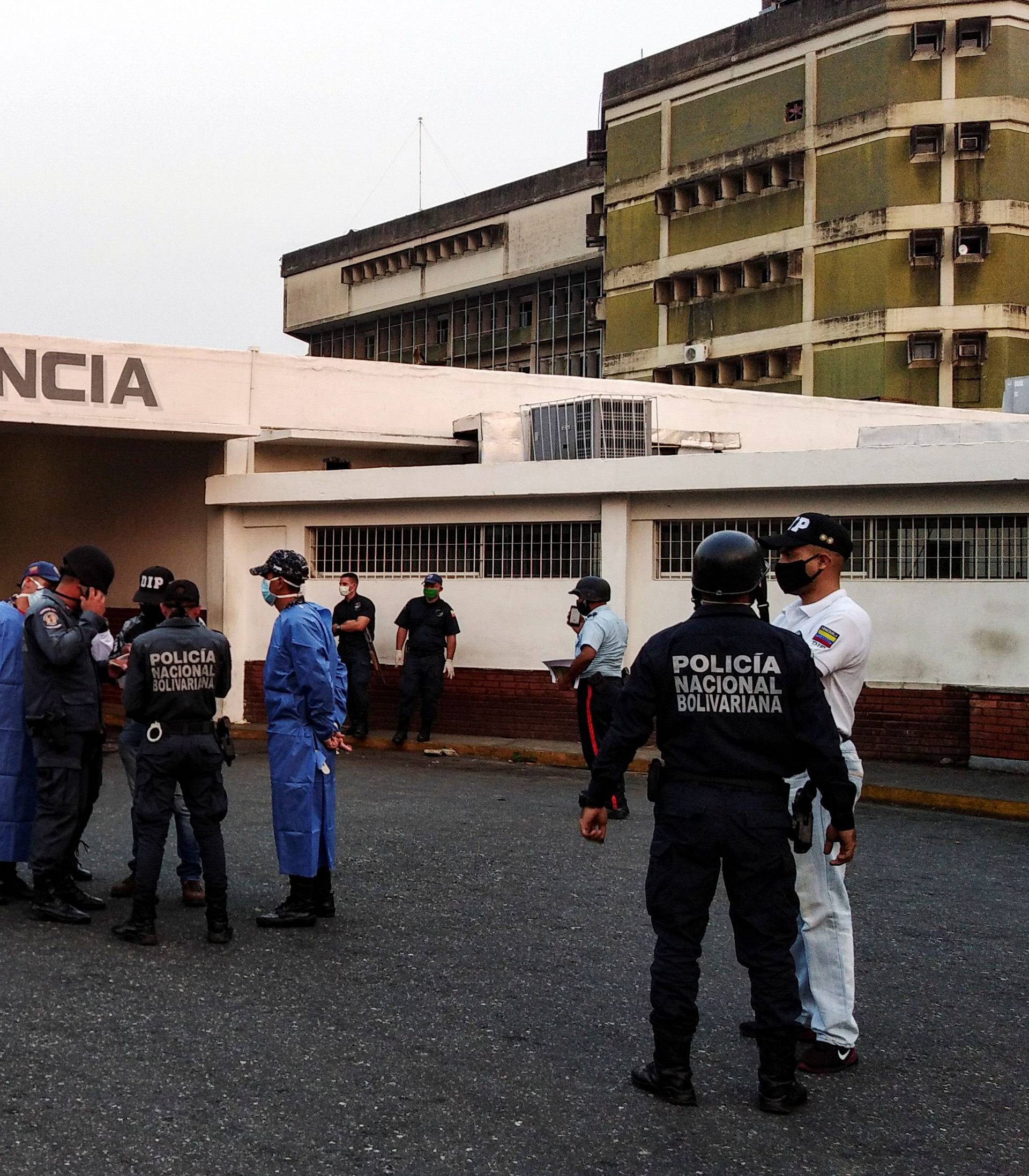 Healthcare workers and members of the Bolivarian national police wait for the arrival of prisoners outside a hospital  after a riot erupted inside a prison in Guanare