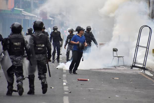 Man walks away from tear gas as supporters of Nasralla clash with police during a protest caused by the delayed vote count for the presidential election in San Pedro Sula