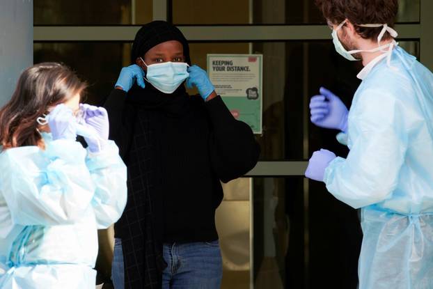 Healthcare workers assist a resident in putting her mask on outside of a public housing tower, reopened following a COVID-19 lockdown, in Melbourne