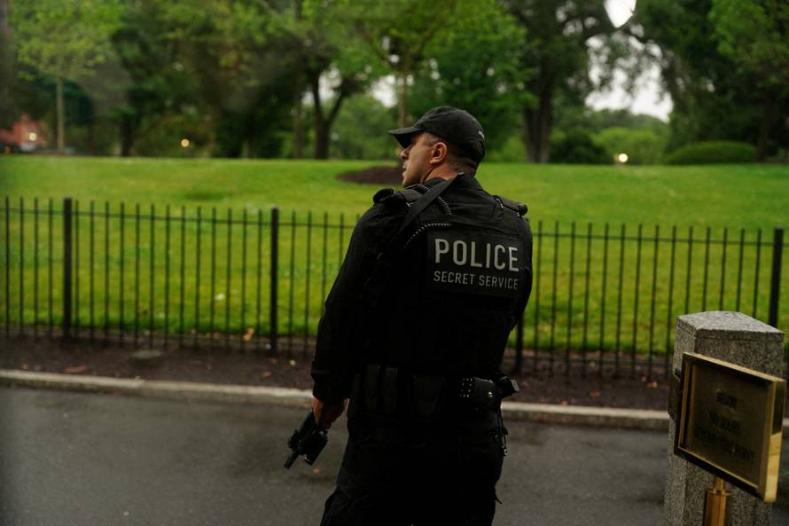 A member of the U.S. Secret Service watches holding his weapon after alleged gunshots were heard nearby, at the White House in Washington