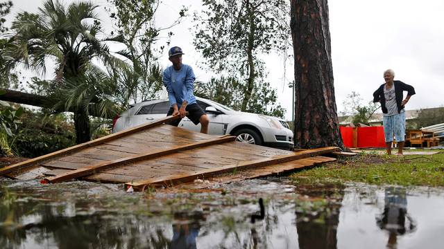 Joseph Howat clears a damaged fence by Hurricane Michael at his business in Panama City Beach