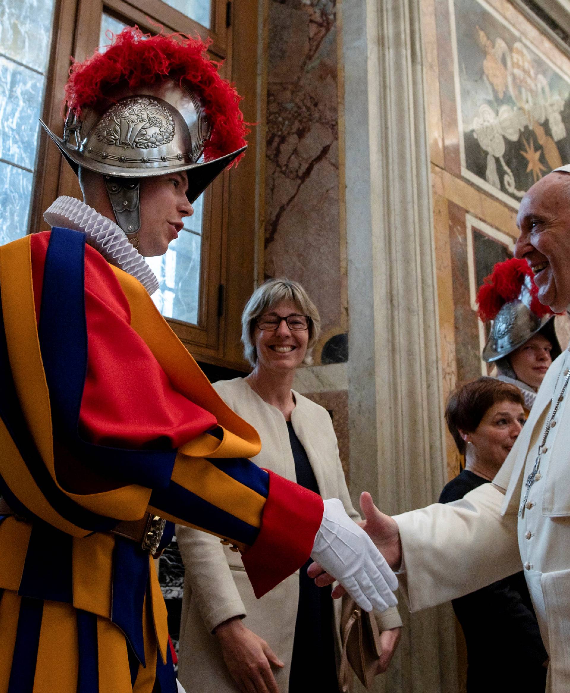 Pope Francis shakes hands with a Swiss guard the day ahead of their swearing-in ceremony at the Vatican
