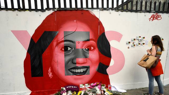 A woman looks at a new mural of Savita Halappanavar with flowers placed beneath it put up on the day of the Abortion Referendum on liberalising abortion laws in Dublin