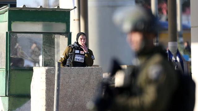 Palestinian woman, who according to the Israeli police was shot and wounded after she attempted to stab Israeli officers, lies on the ground at Qalandiya checkpoint near the West Bank city of Ramallah