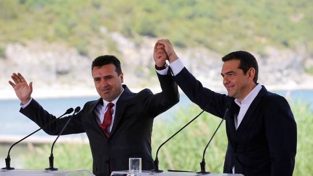 Greek Prime Minister Alexis Tsipras and Macedonian Prime Minister Zoran Zaev gesture before the signing of an accord to settle a long dispute over the former Yugoslav republic's name in the village of Psarades