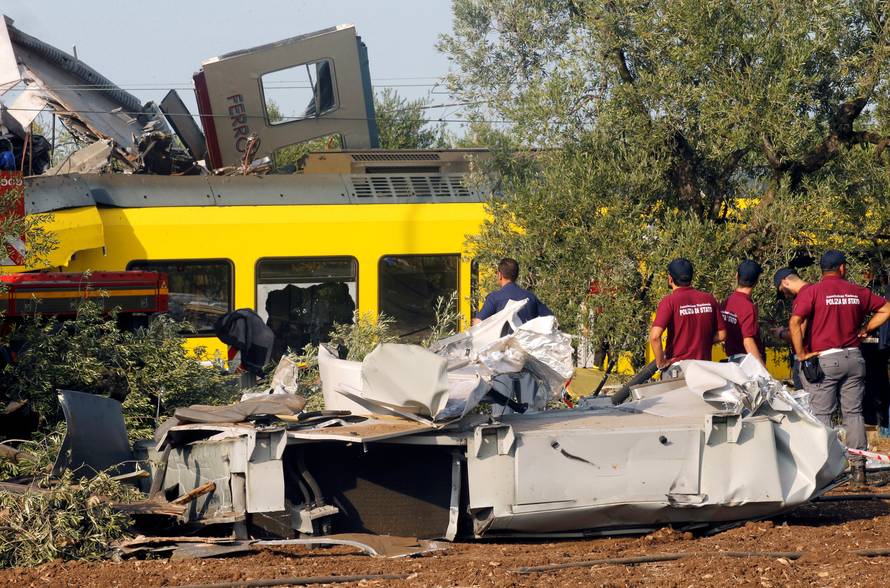 Rescuers stand at the site where two passenger trains collided in the middle of an olive grove in the southern village of Corato