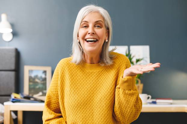 Happy caucasian senior woman making video call at home smiling and gesturing to camera. Communication, happiness, retirement and domestic life concept.