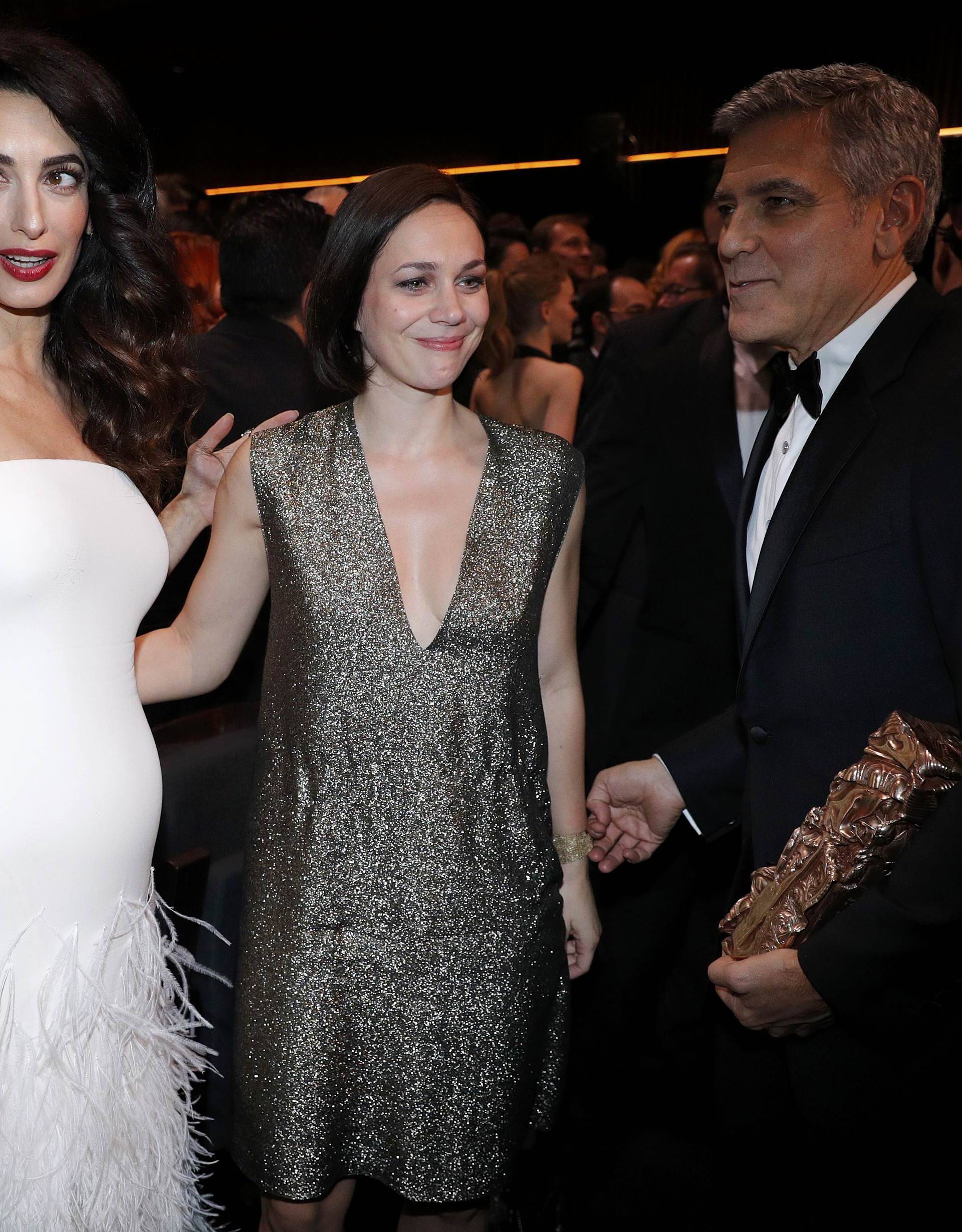 Actor George Clooney holds his Honorary Cesar Award as he leaves with his wife Amal and Nathalie Pechalat at the end of the 42nd Cesar Awards ceremony in Paris