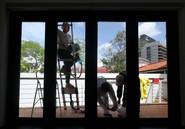 Bee rescuer Clarence Chua vacuums stray bees as teammates Lon Voon and Jian Ping clean up the area after a bee nest is removed from the roof of an apartment in Singapore