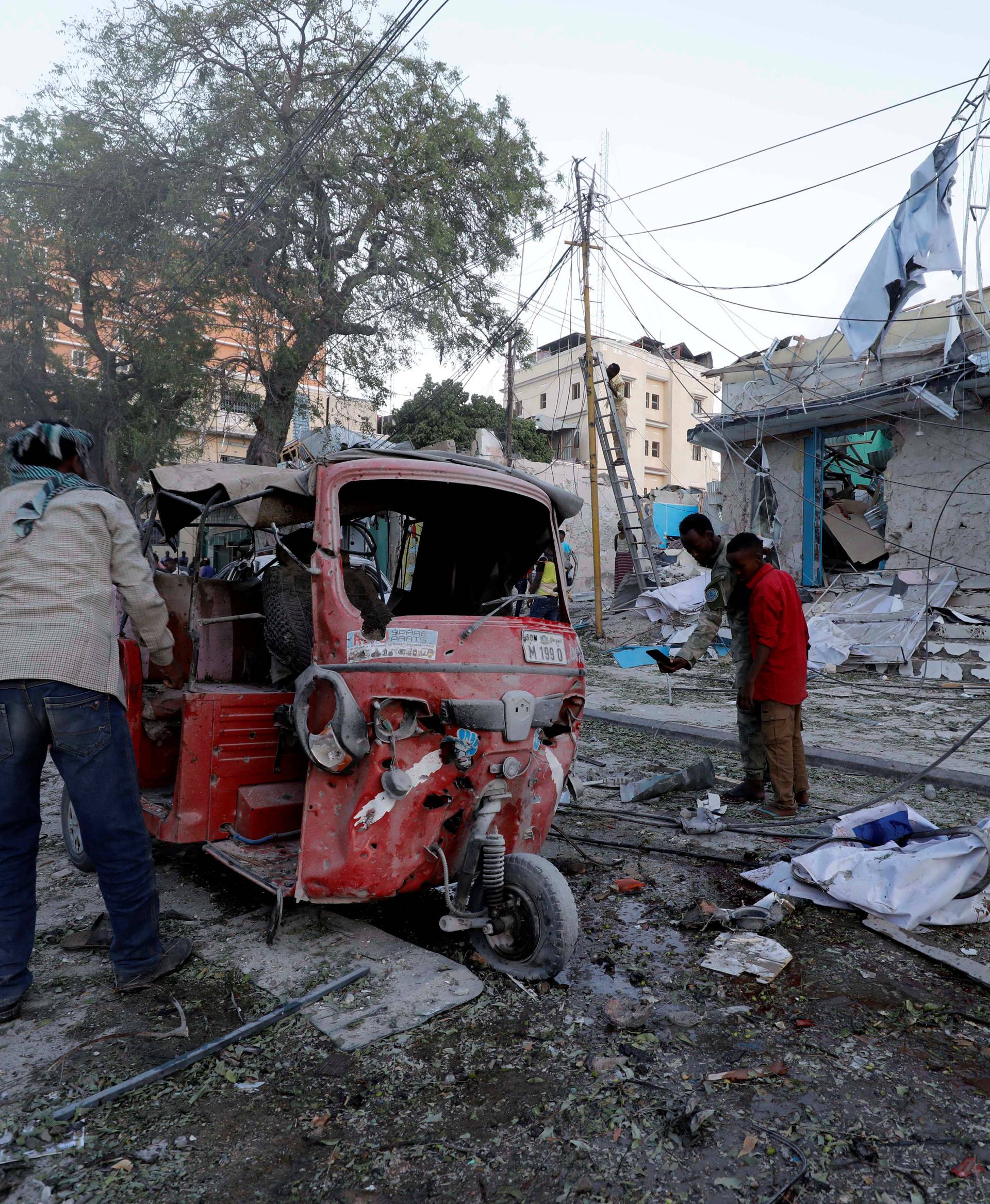 People watch the rubble near damaged buildings after a suicide car bomb exploded, targeting a hotel in a business center in Maka Al Mukaram street, Mogadishu