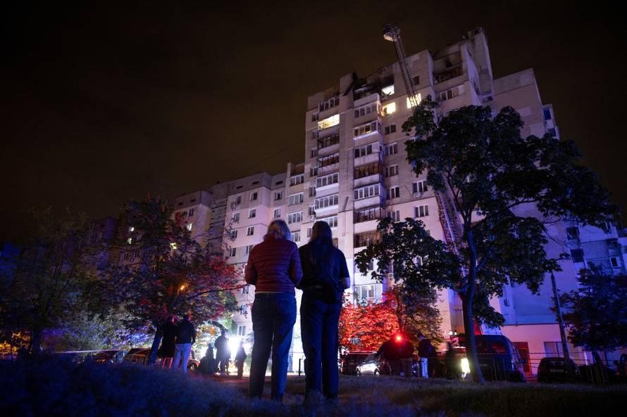 People look at an apartment building that was damaged in a Russian drone attack in Kyiv