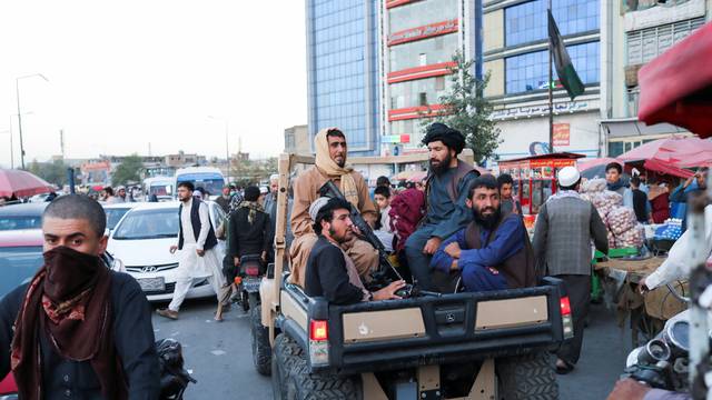 Taliban soldiers sit on the back of a truck in a street in Kabul