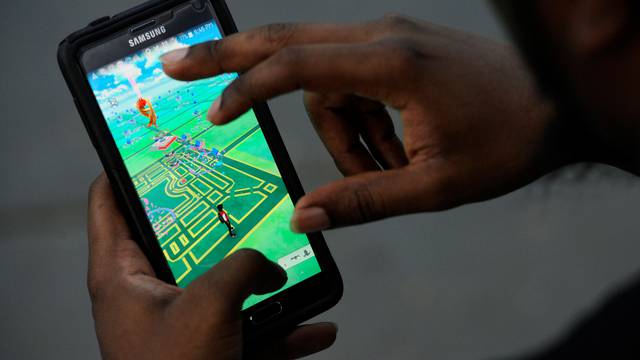 A virtual map of Bryant Park is displayed on the screen as a man plays the augmented reality mobile game "Pokemon Go" by Nintendo in New York City