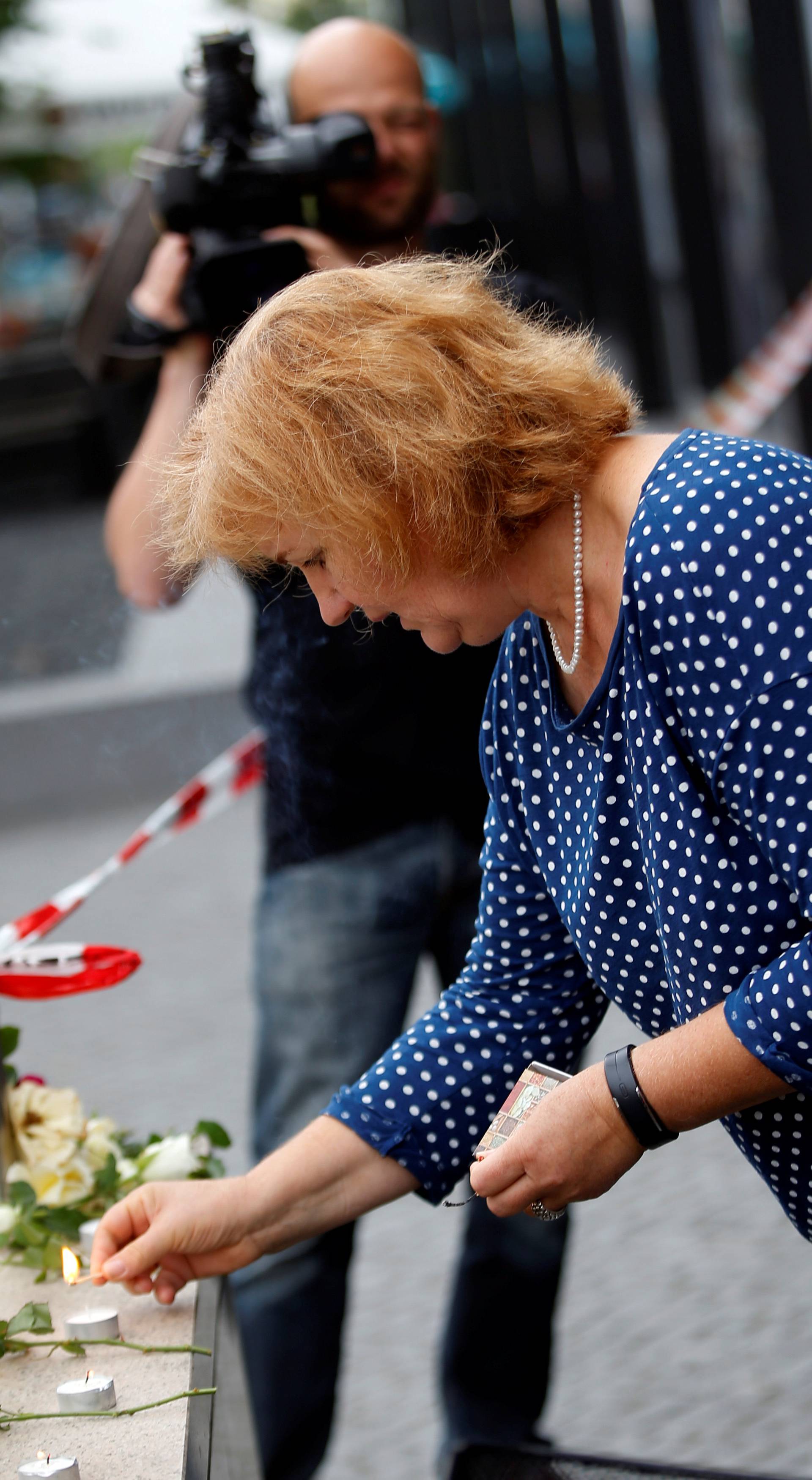 A woman lights candles near the Olympia shopping mall, where yesterday's shooting rampage started in Munich
