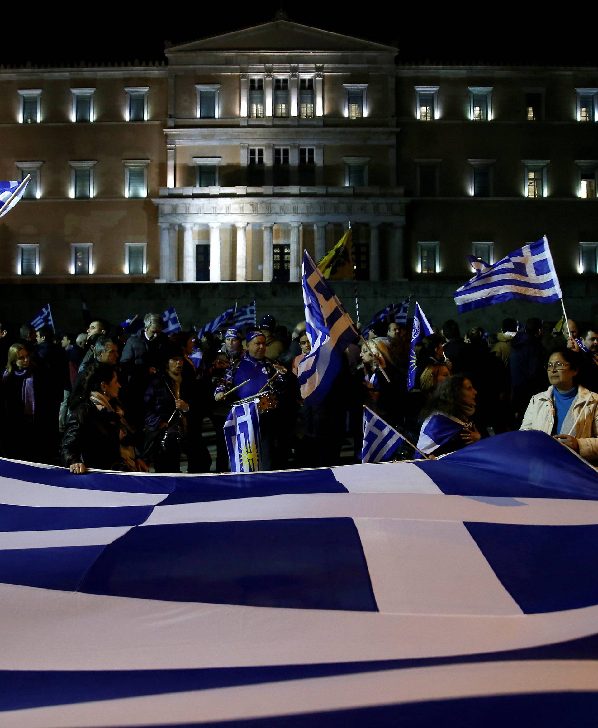 Protesters hold a giant Greek national flag during a demonstration against the agreement reached by Greece and Macedonia to resolve a dispute over the former Yugoslav republic's name,  in front of the parliament building in Athens