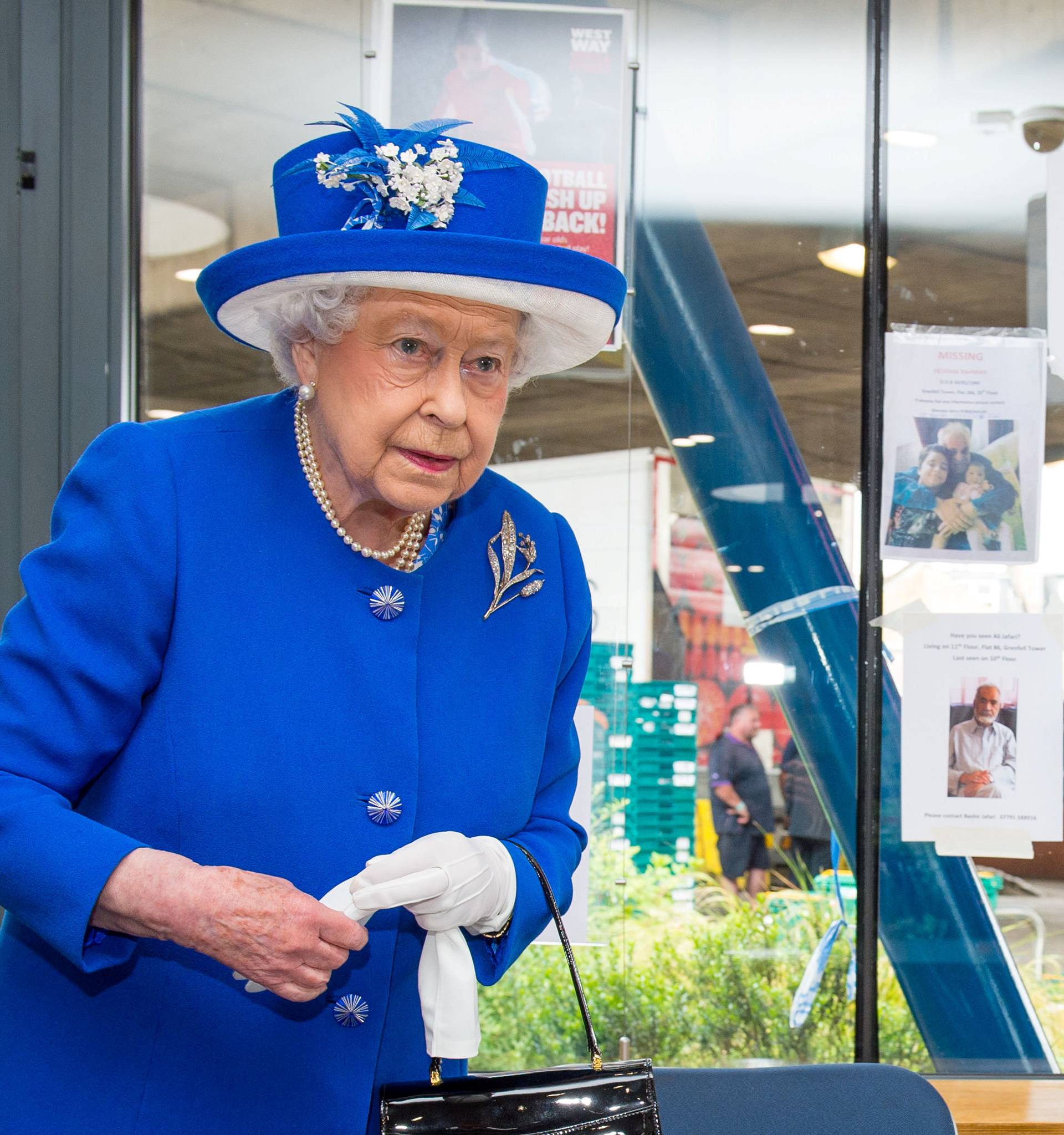 Britain's Queen Elizabeth walks past missing person posters during a visit to the Westway Sports Centre following the fire at the Grenfell Tower block, in north Kensington, West London