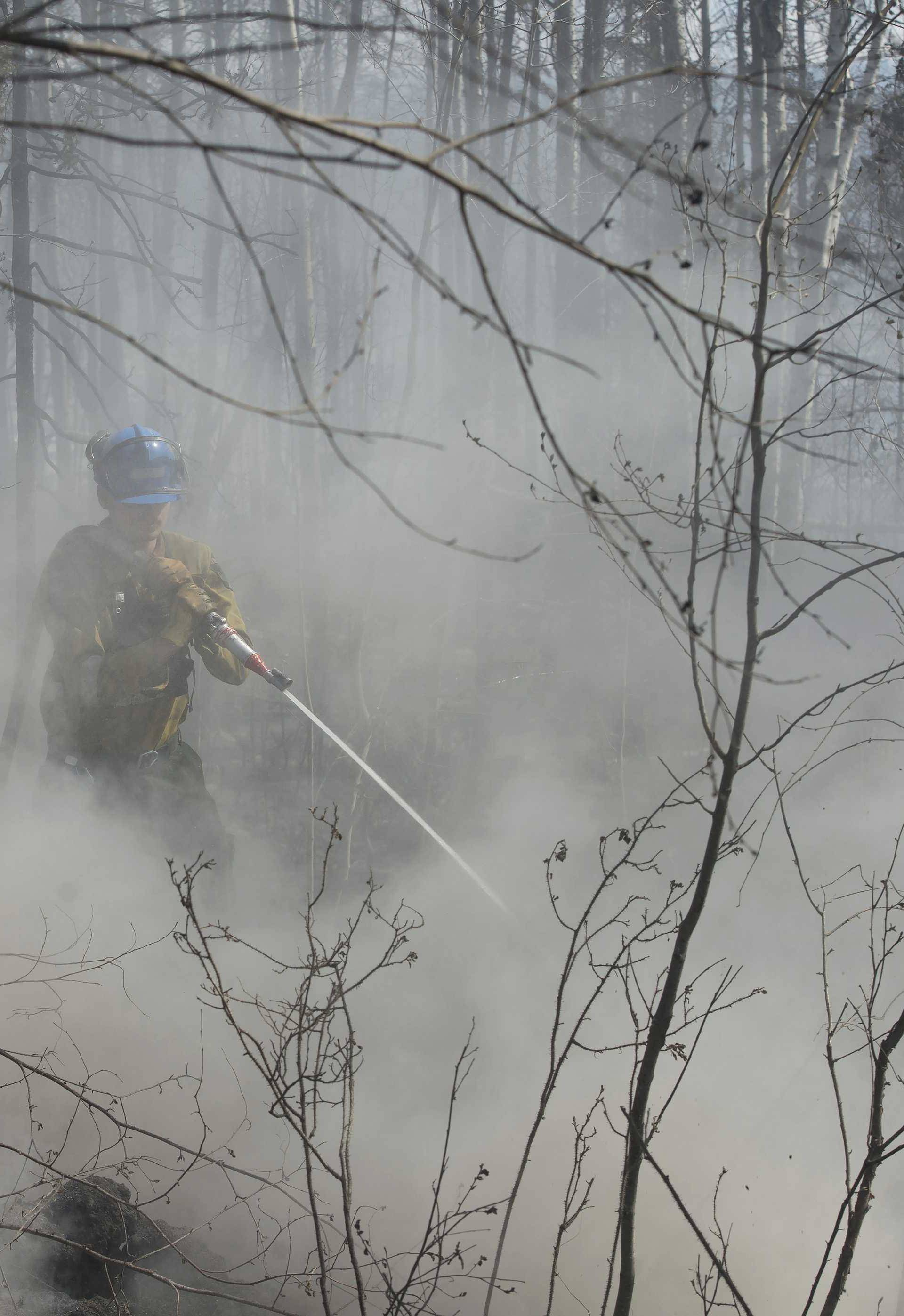 A member of Wildfire Management Alberta's Wild Mountain Unit out of Hinton, hoses down hotspots in the Parsons Creek area of Fort McMurray