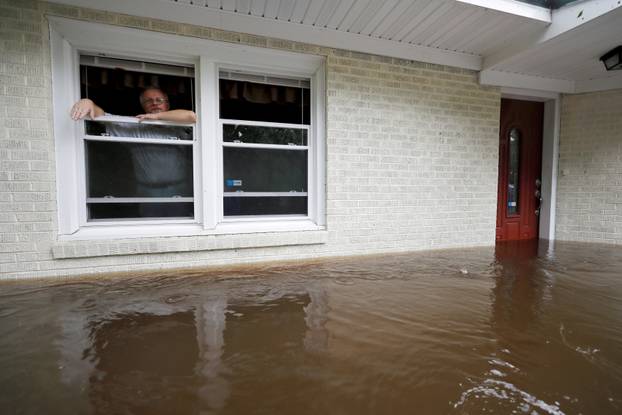 Gavrilovic peers out the window of his flooded home while considering whether to leave with his wife and pets as waters rise in North Carolina