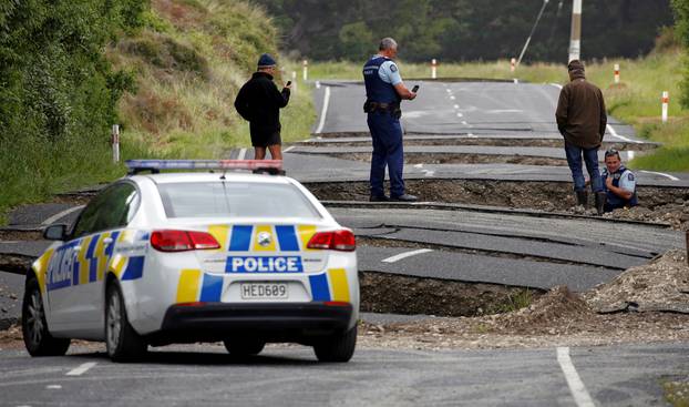 Policemen and locals look at damage following an earthquake, along State Highway One near the town of Ward, New Zealand