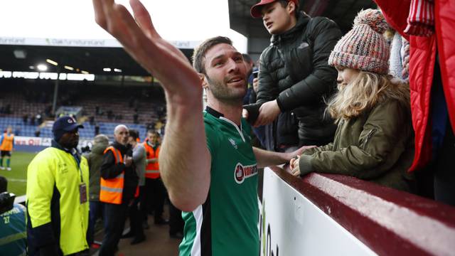 Lincoln's Jamie McCombe celebrates after the match with a young girl