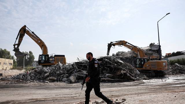 An Israeli policeman walks past a destroyed police station that was the site of a battle following a mass-infiltration by Hamas gunmen from the Gaza Strip, in Sderot