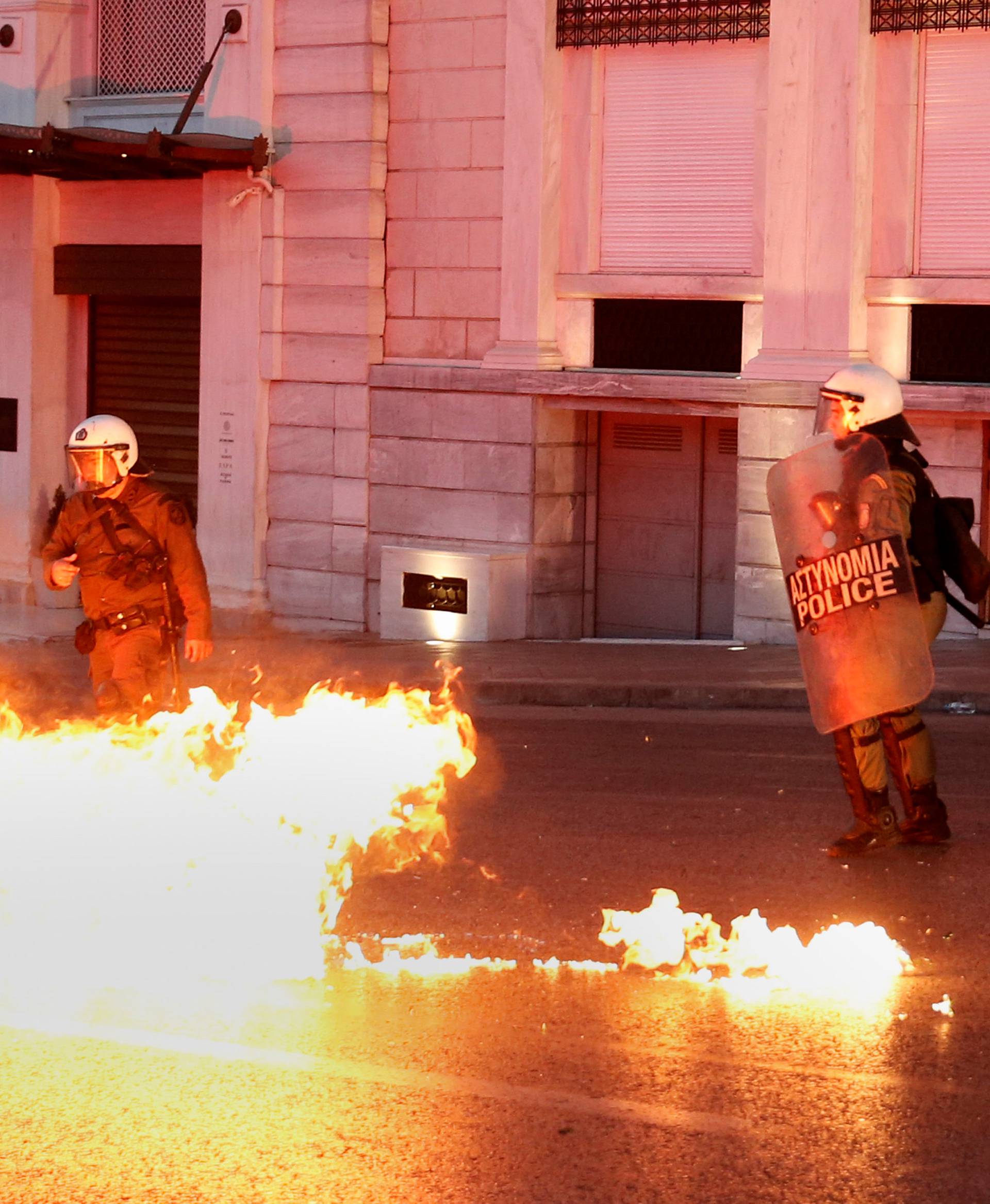 Greek riot police officers dodge a petrol bomb thrown by protesters during minor clashes following a protest outside parliament in central Athens