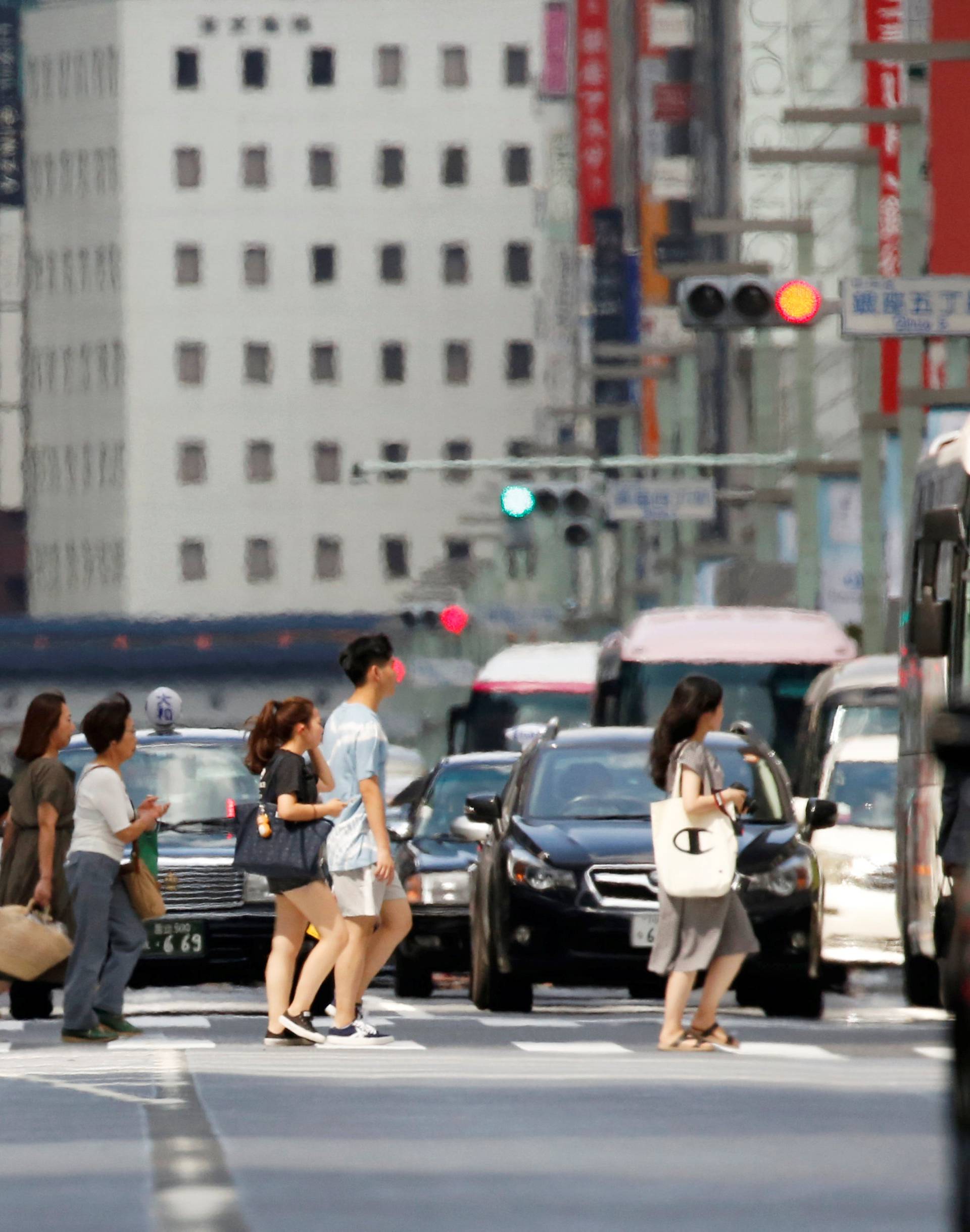 Passersby walk on a street in a heat haze during a heatwave in Tokyo