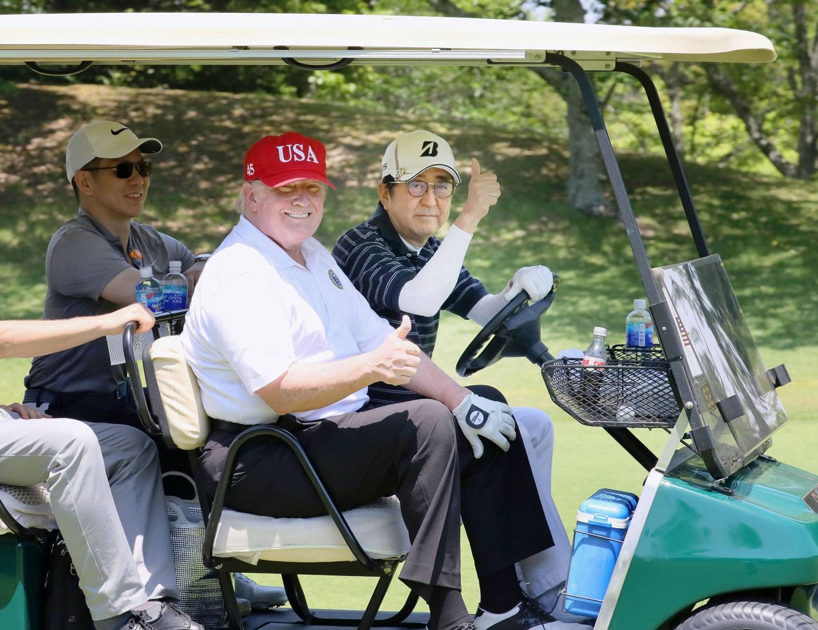 U.S. President Donald Trump sits on a cart as Japanese Prime Minister Shinzo Abe drives the cart as they play golf at Mobara Country Club in Mobara