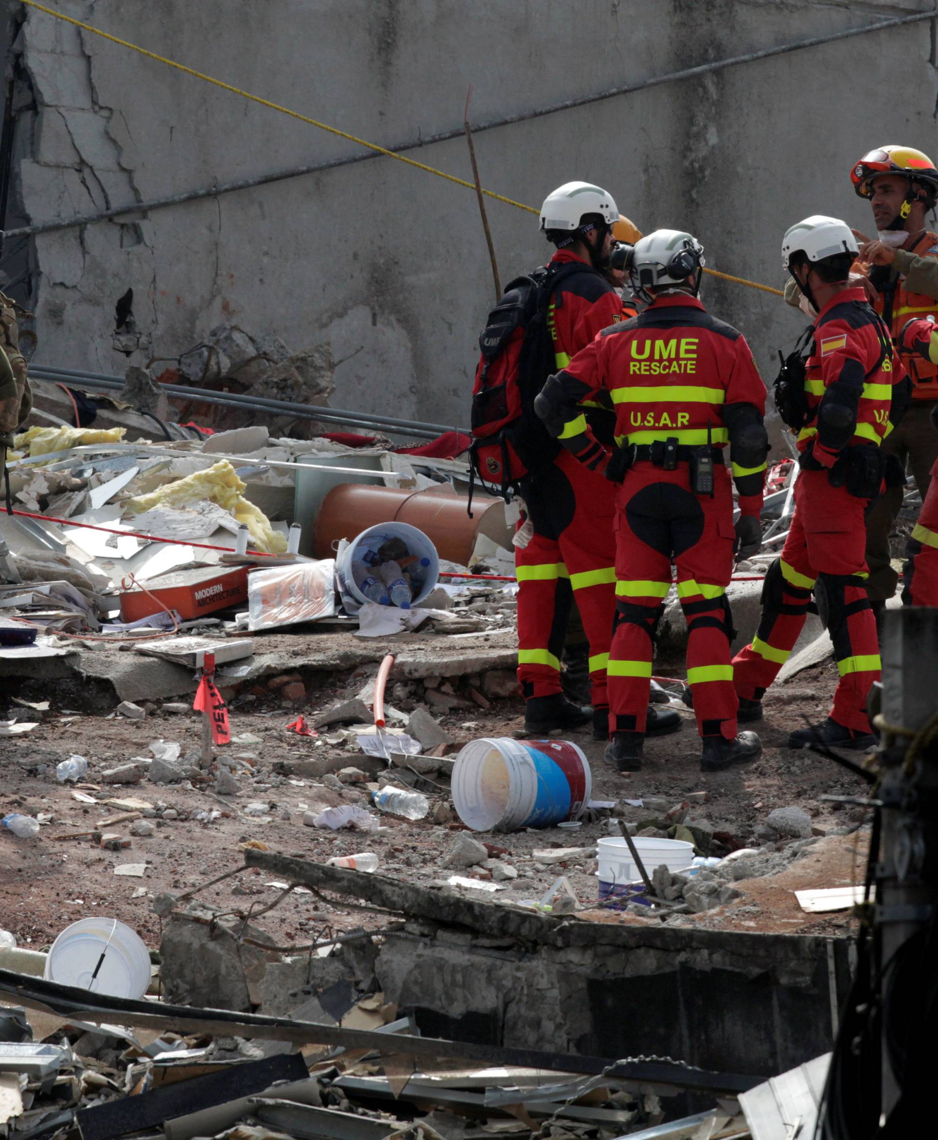Members of Israeli and Spanish rescue teams talk while standing on the rubble of a collapsed building, after an earthquake, in Mexico City