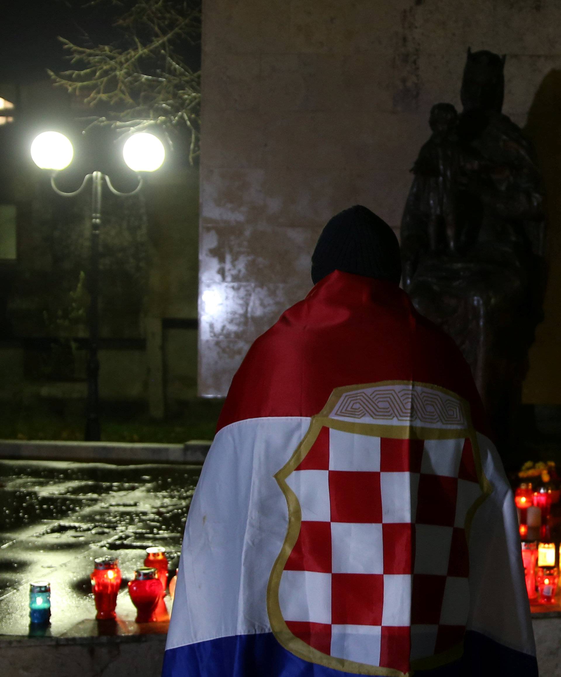 A Bosnian Croat, wrapped in a flag of unrecognised wartime Croat statelet, prays for the convicted general Slobodan Praljak who killed himself seconds after the verdict in the U.N. war crimes tribunal in The Hague, in Mostar