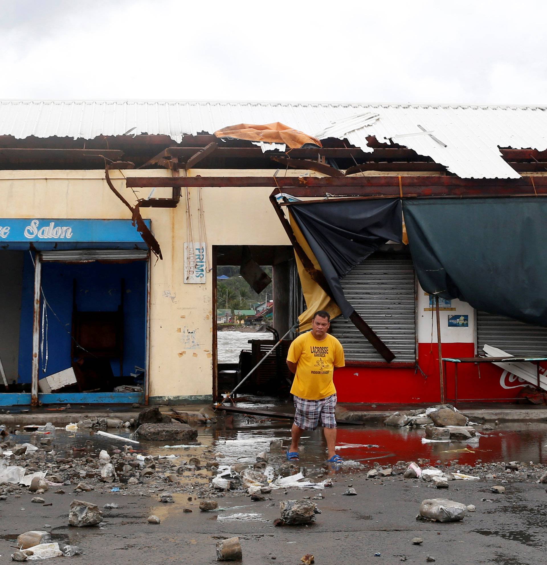 A resident walks in front of a partially damaged port building and debris swept from the sea at the height of Typhoon Nock-Ten in Mabini, Batangas