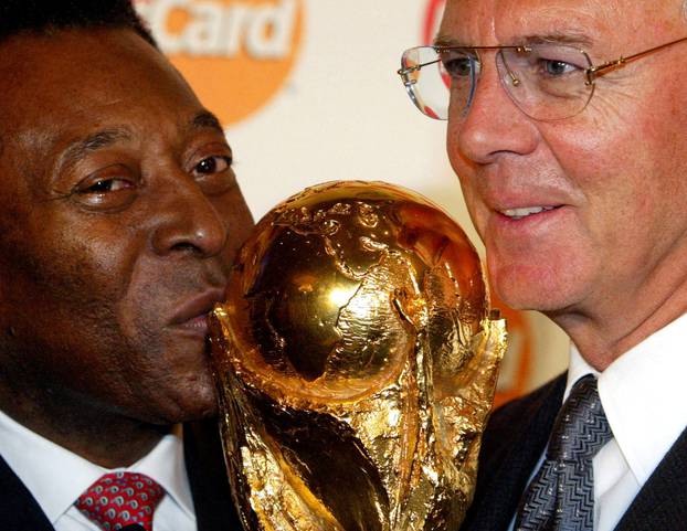 FILE PHOTO: BRAZILIAN SOCCER LEGEND PELE KISSES WORLD CUP NEXT TO GERMAN LEGEND BECKENBAUER IN BERLIN.