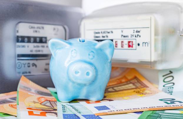 Small,Blue,Piggy,Bank,And,Euro,Cash,Near,An,Electricity