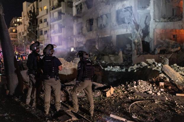 An Israeli firefighter works to put out a fire on a car at the site of a projectile impact, in Tel Aviv