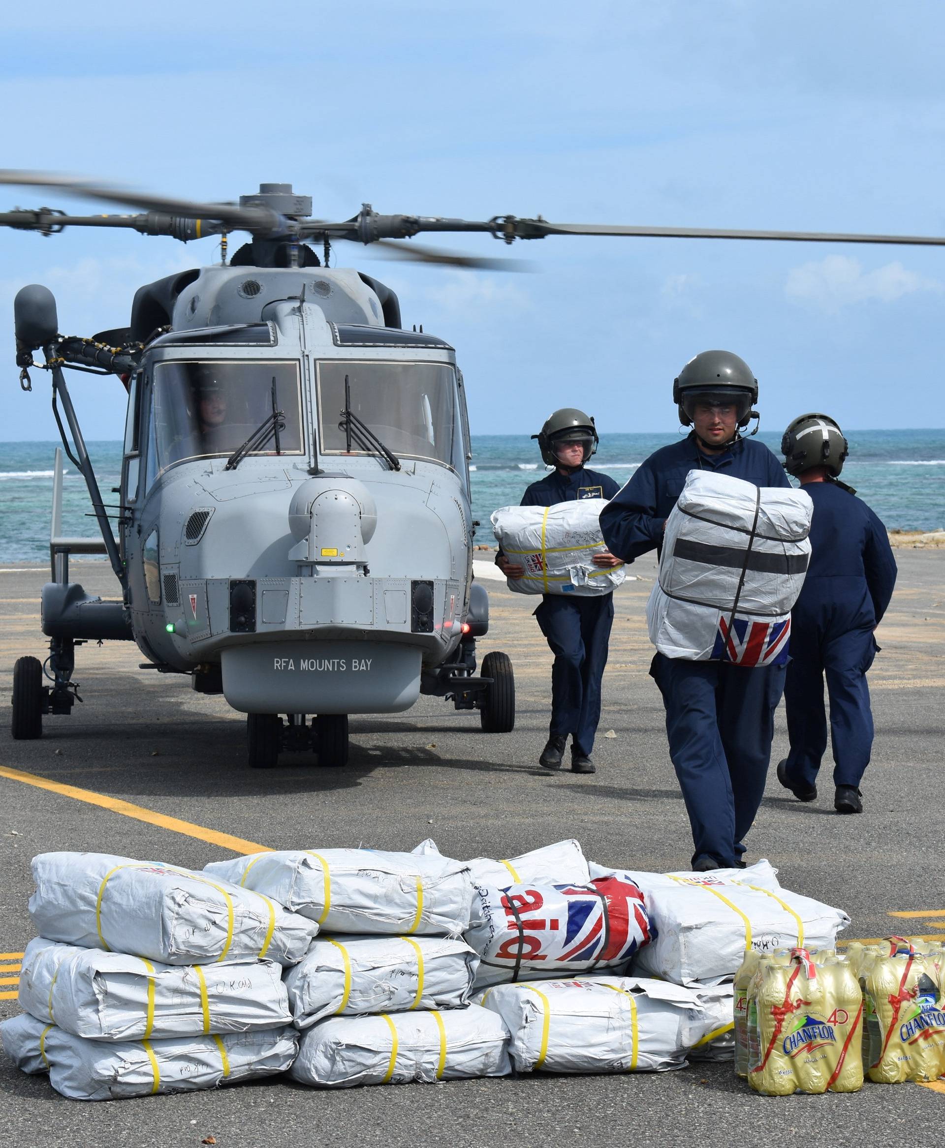 Royal Navy ground crew unload disaster supplies from a Wildcat helicopter at Tortola airport