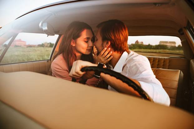 Pretty lovely couple kissing while sitting inside car