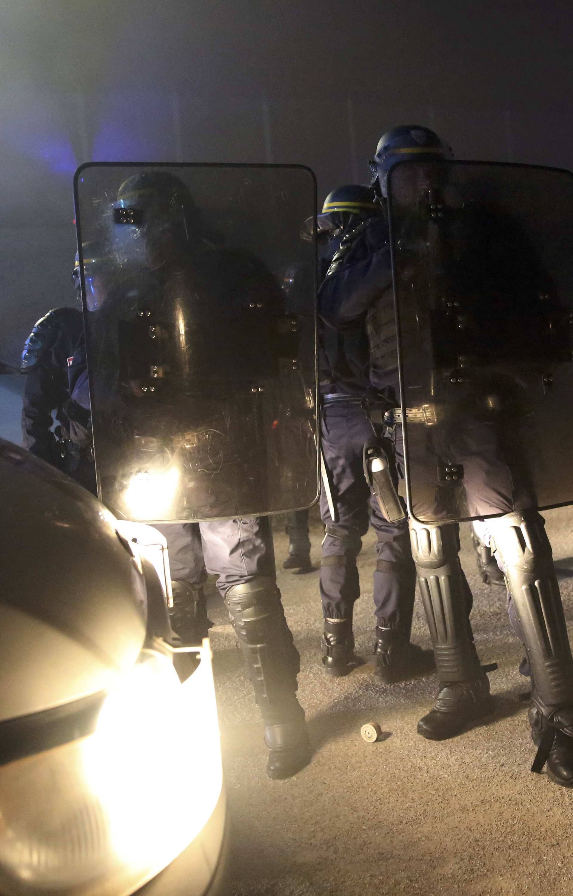 French CRS riot police stand by the razor-wire topped fence which secures the road approach to the city and dissuades migrants from trying to reach Britain on lorries on the eve of the evacuation and dismantlement of the camp called the "Jungle" in Calais