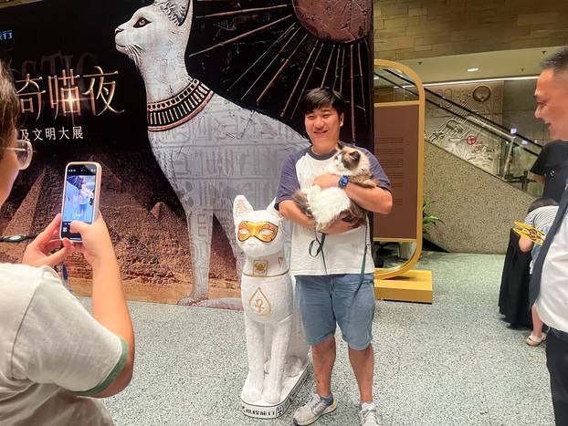 A cat visitor poses with its owner in the entrance hall of Shanghai Museum's "Meow Night\