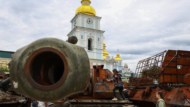 A child plays on top of destroyed Russian military vehicles and weapons outside St Michael's Cathedral in Kyiv