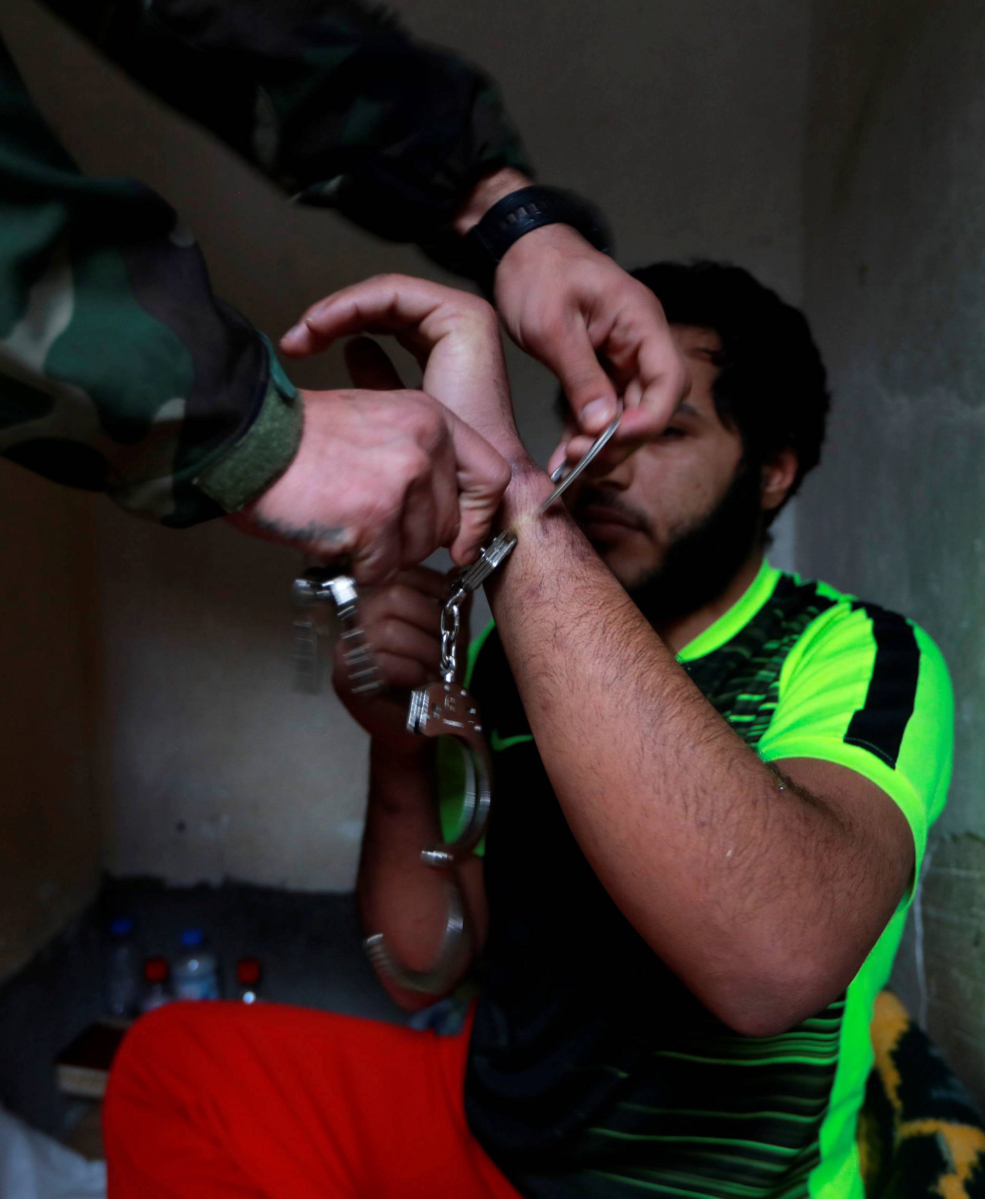An Islamic State member has his cuff removed by a counter-terrorism agent inside his prison cell  in Sulaimaniya