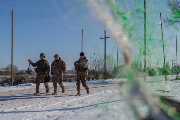 Ukrainian servicemen walk along a street under an anti-drone net near a front line in Donetsk region