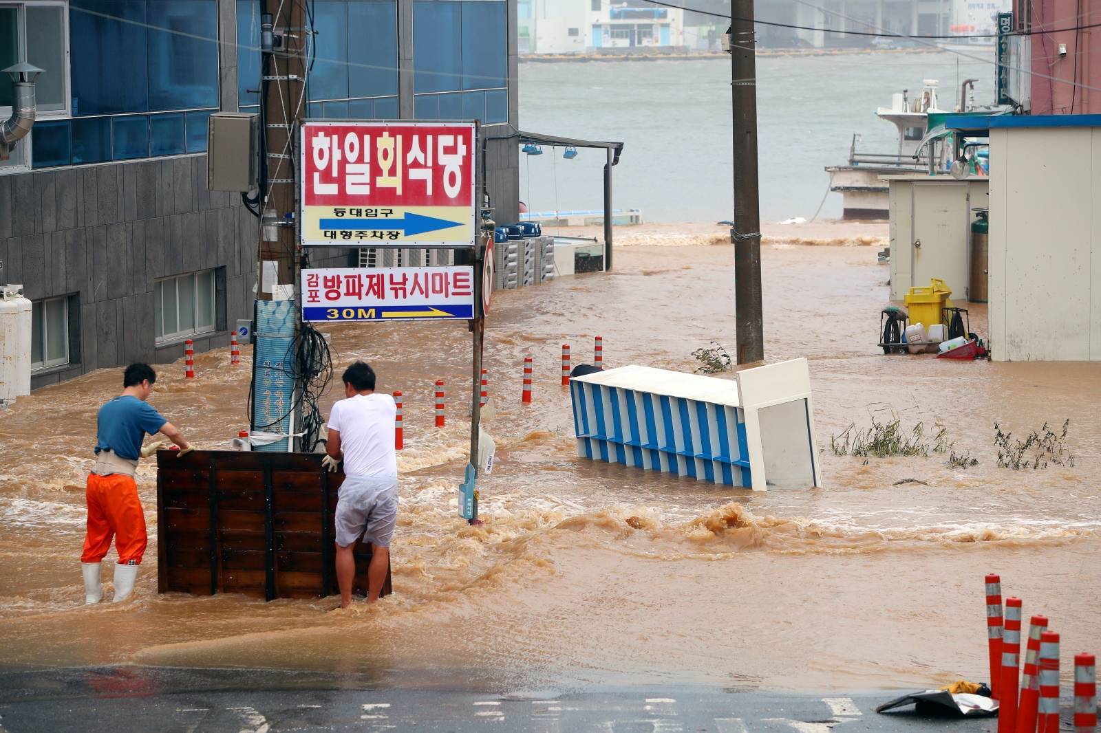 Men stand on a street submerged by typhoon Haishen in Gyeongju