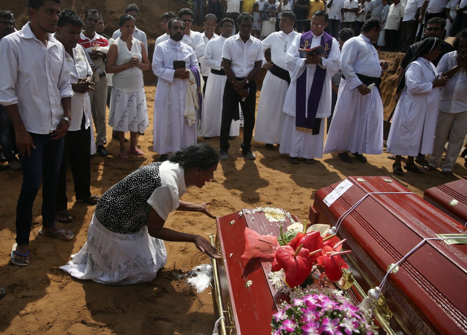 A woman reacts next to a coffin during a mass burial of victims at a cemetery near St. Sebastian Church in Negombo