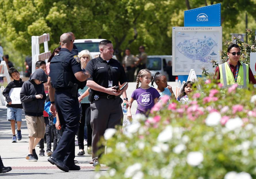 Police officers escort students from a campus of California State University - San Bernardino, where they were evacuated after a shooting at North Park Elementary School