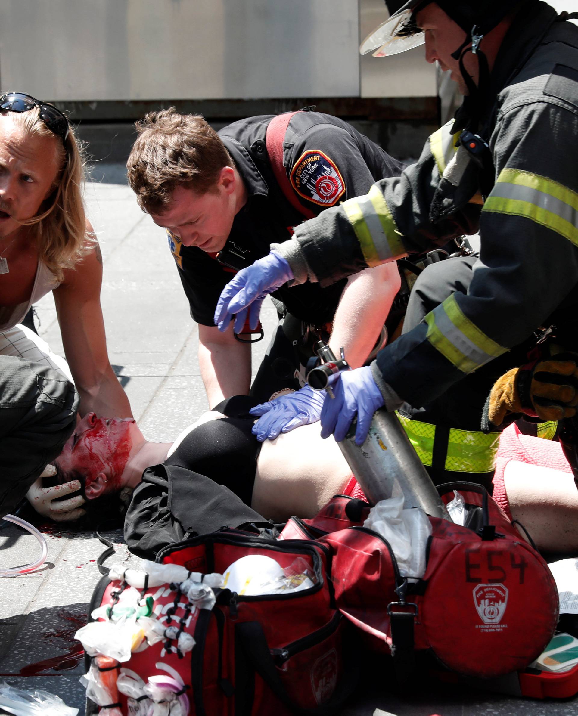 An injured woman is helped by emergency workers as she lies on the sidewalk in Times Square after a speeding vehicle struck pedestrians on the sidewalk in New York City
